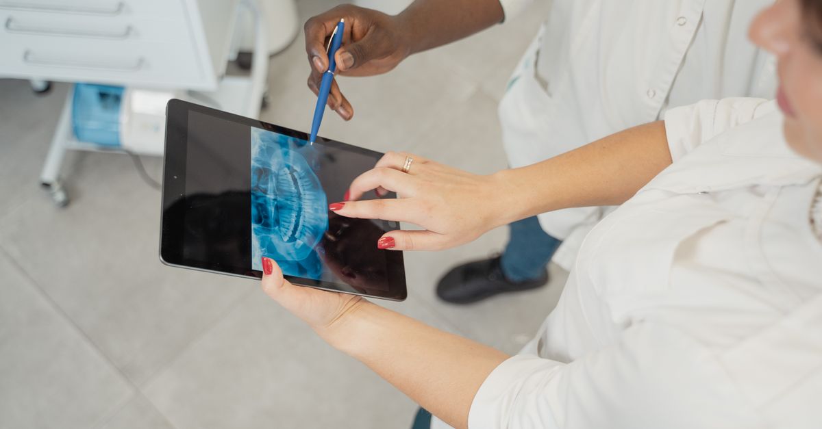 Dentista usando tablet para emitir prescrição digital em consultório odontológico