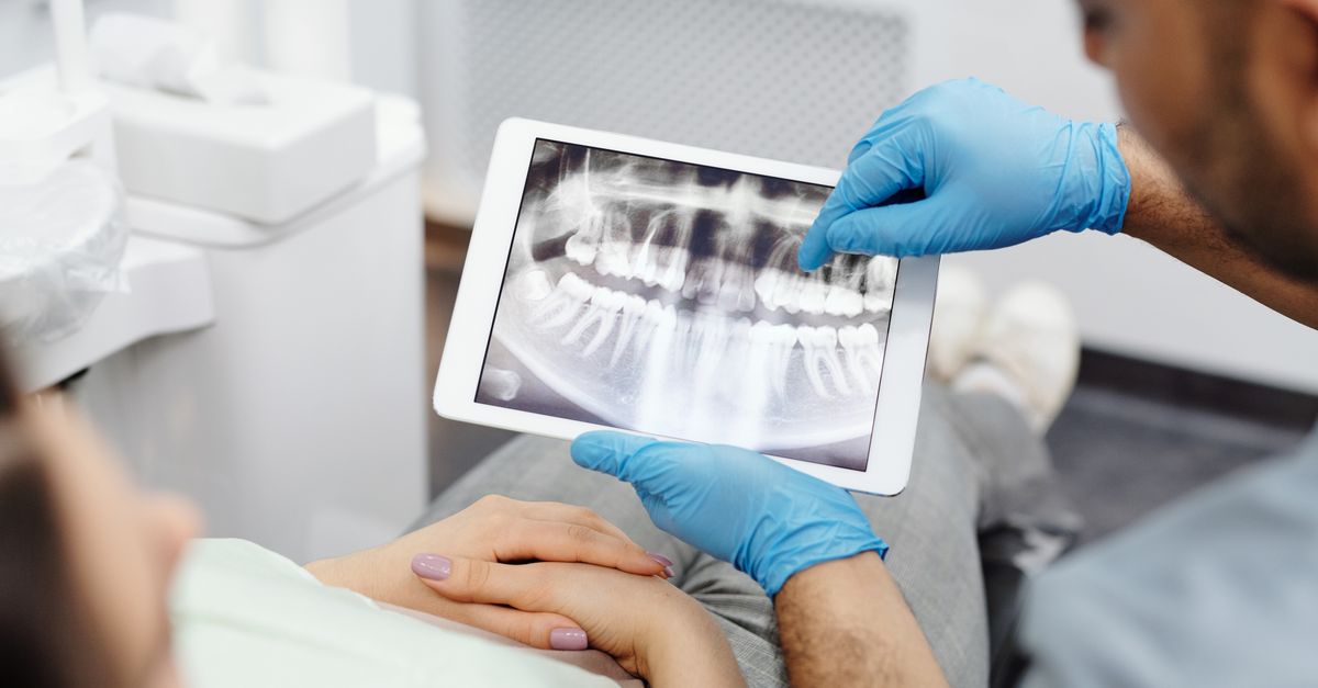 Dentista acessando sistema de prescrição digital em tablet no consultório odontológico