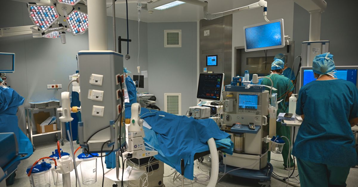 Equipe médica em sala de emergência analisando monitores de sinais vitais de paciente